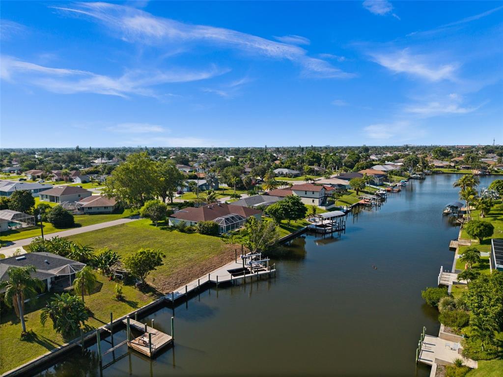 An aerial view of a residential neighborhood featuring houses along a canal with private docks — 3022 SE 6TH AVENUE, CAPE CORAL, FL