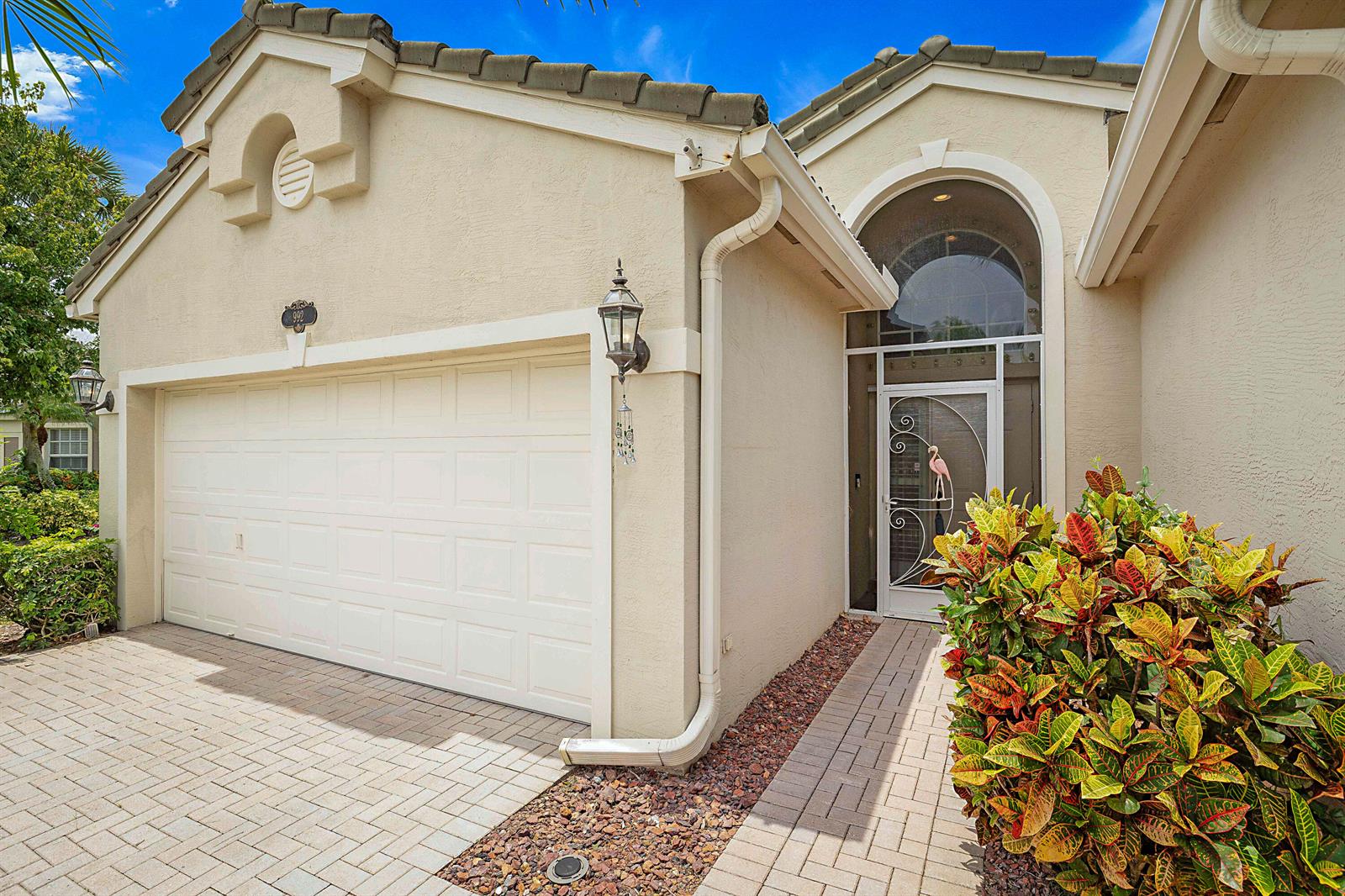 The exterior of a beige house features a two-car garage and a glass-paned front door — 992 SE Westminster Place, Stuart FL 34997, STUART, FL