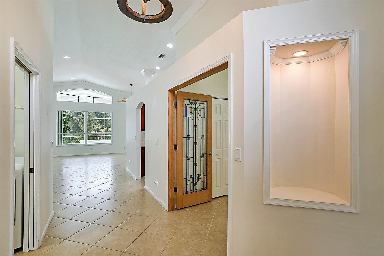 A hallway with tiled floors leads to a living area featuring a stained-glass door — 992 SE Westminster Place, Stuart FL 34997, STUART, FL