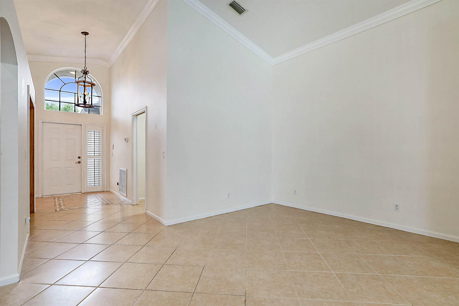 An entryway with tiled floors, a high ceiling, and a front door with a transom window — 992 SE Westminster Place, Stuart FL 34997, STUART, FL