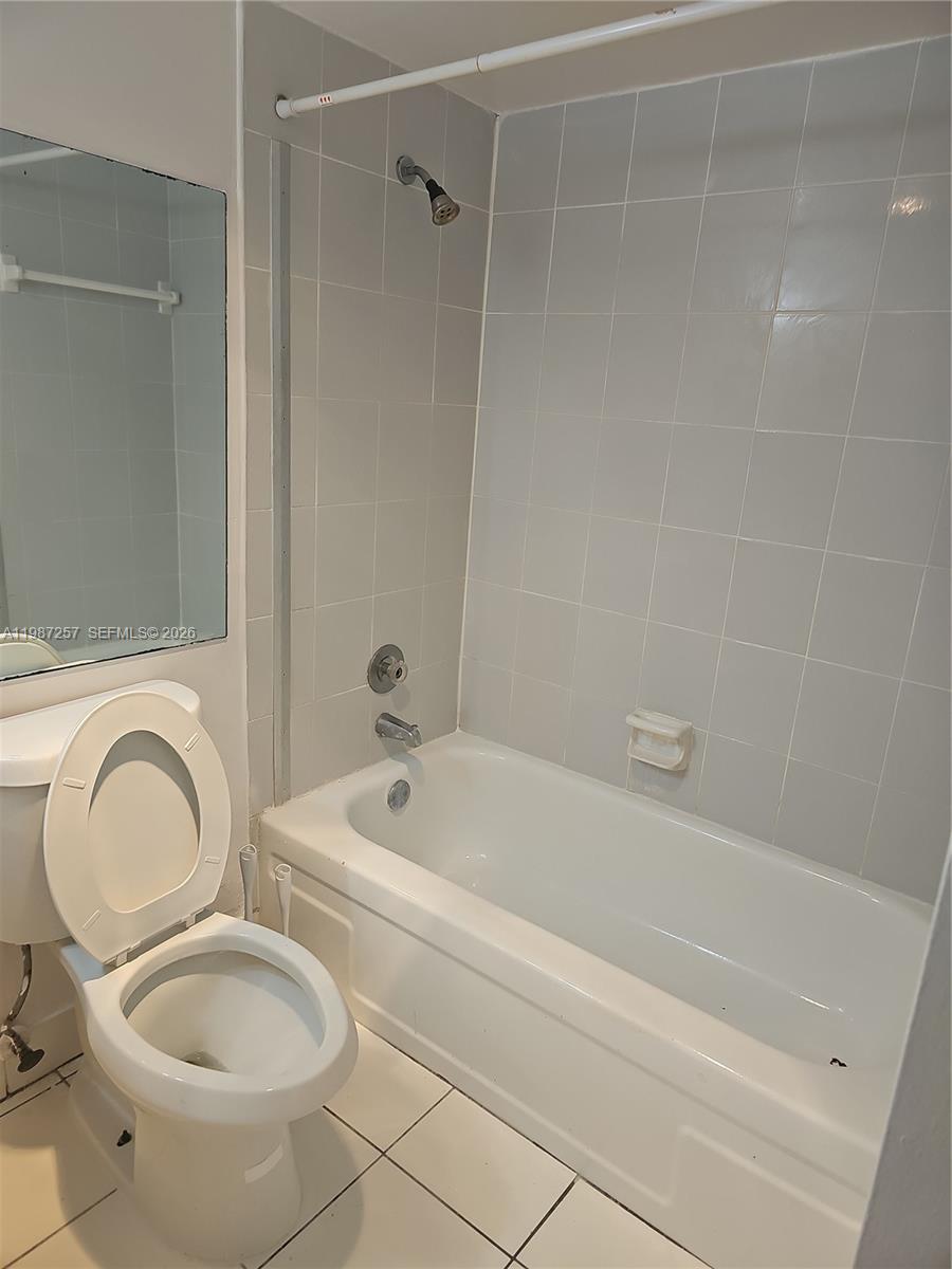 A bathroom features a white toilet, a bathtub with a showerhead, and light-colored wall tiles — 3301 Spanish Moss Ter # 708, Lauderhill FL 33319, LAUDERHILL, FL