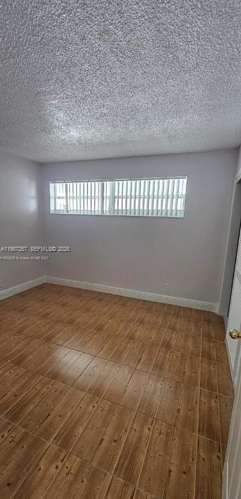 An empty bedroom features light-colored walls, a textured ceiling, and wood-look tile flooring — 3301 Spanish Moss Ter # 708, Lauderhill FL 33319, LAUDERHILL, FL