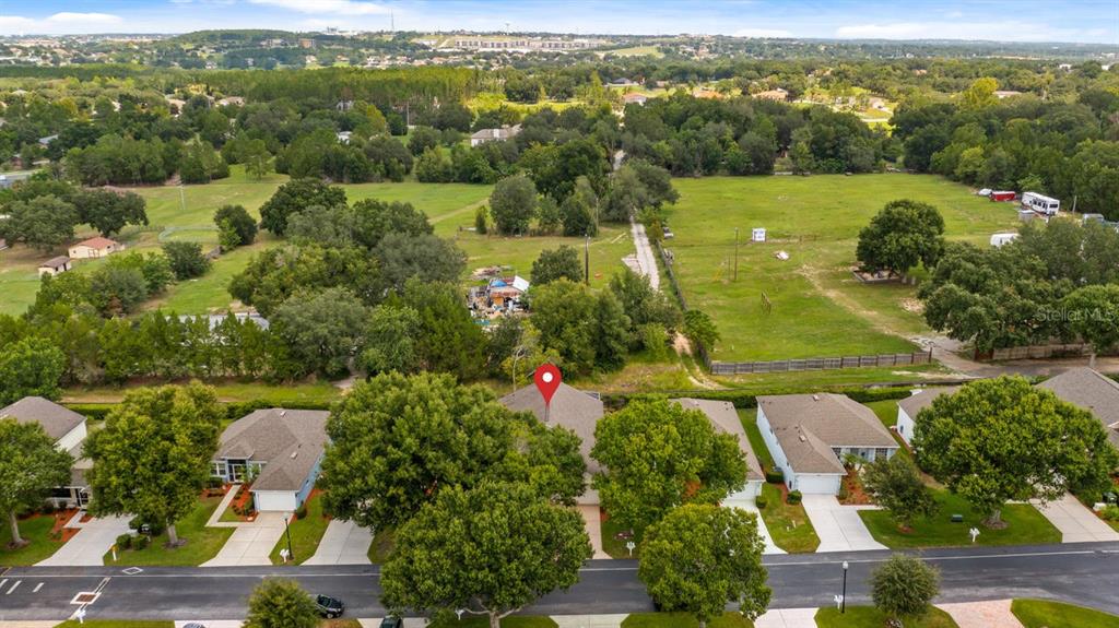 An aerial view shows a residential street with houses and a large, grassy field behind — 4127 CAPLAND AVENUE, CLERMONT, FL