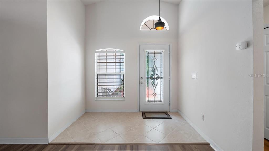 An entryway with tile flooring, a front door with decorative glass, and a vaulted ceiling — 4127 CAPLAND AVENUE, CLERMONT, FL