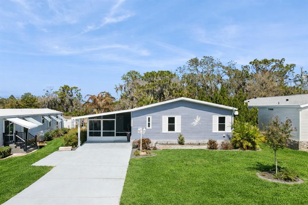 A blue single-story house with a screened-in porch and a concrete driveway — 8568 BREEZE HILL DRIVE, LAKE WALES, FL