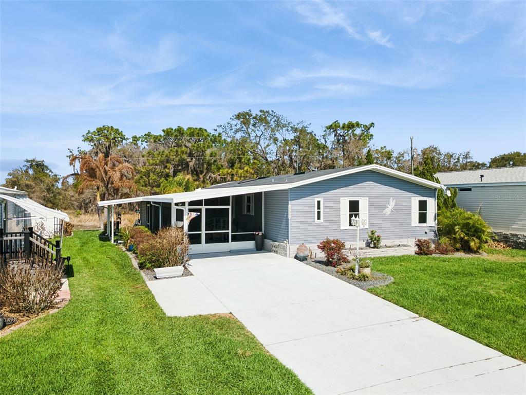 A light blue manufactured home with a concrete driveway and a screened-in front porch — 8568 BREEZE HILL DRIVE, LAKE WALES, FL