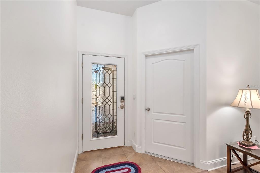 An entryway features a front door with a decorative glass insert and tile flooring — 2309 ANGEL FISH LOOP, LEESBURG, FL