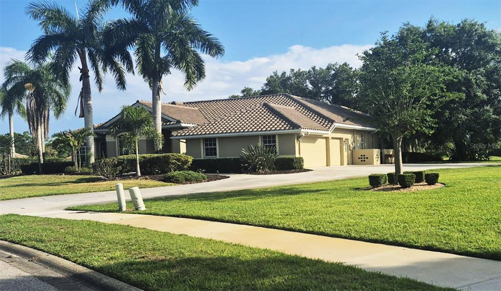 A single-story tan house with a tiled roof and a large driveway surrounded by palm trees — 8333 EAGLE LAKE DRIVE, SARASOTA, FL