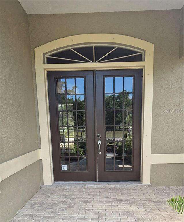 A pair of dark brown French doors with glass panes and a decorative arched transom window — 8333 EAGLE LAKE DRIVE, SARASOTA, FL
