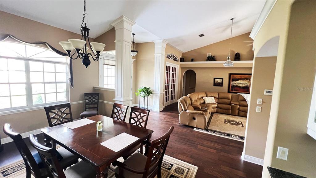 A dining area with a wooden table and chairs opens into a living room — 8333 EAGLE LAKE DRIVE, SARASOTA, FL