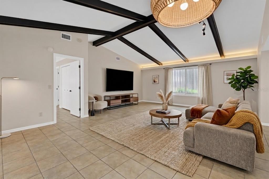 A living room features vaulted ceilings with dark beams, tile flooring, and a large rug — 704 BIMINI LANE, PUNTA GORDA, FL