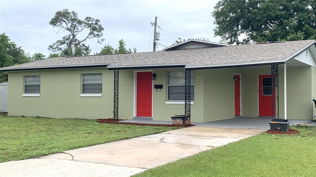 A single-story house with light green concrete block walls, a red front door, and carport — 810 SWISS LANE, ORLANDO, FL