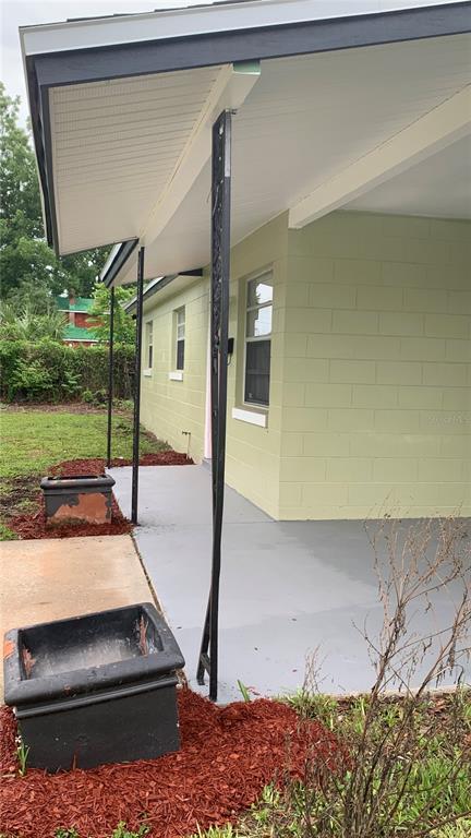 A covered concrete porch features black decorative metal support columns against a light green wall — 810 SWISS LANE, ORLANDO, FL