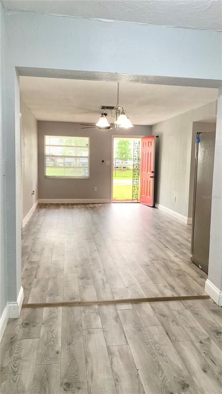 An open living area features light wood-look flooring, a ceiling light fixture, and a red door — 810 SWISS LANE, ORLANDO, FL