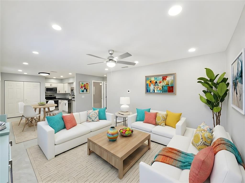 A bright living room features white sofas, a wooden coffee table, and an open kitchen — 2941 SHORE DRIVE UNIT A, SAFETY HARBOR, FL