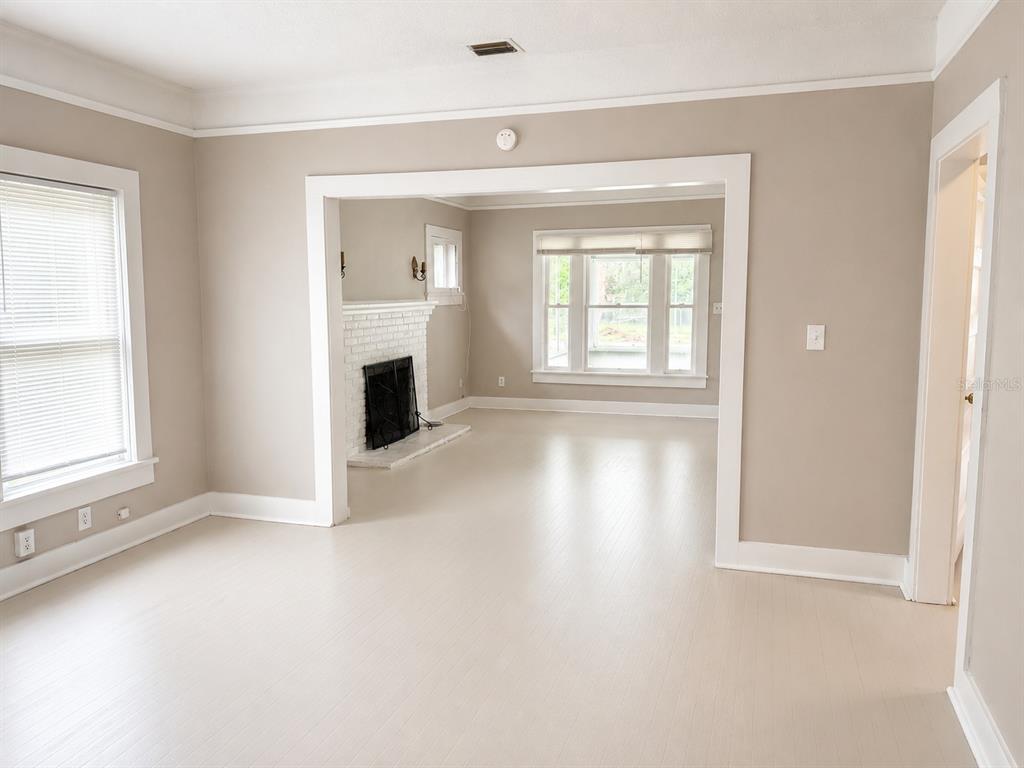 An interior view shows a living room with light-colored flooring, beige walls, and a fireplace — 712 MCKENZIE STREET, LEESBURG, FL