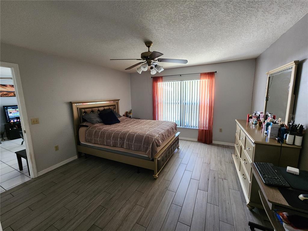 A bedroom features a bed, dresser, ceiling fan, and light-colored wood-look tile flooring — 2814 WILDER PARK DRIVE, PLANT CITY, FL
