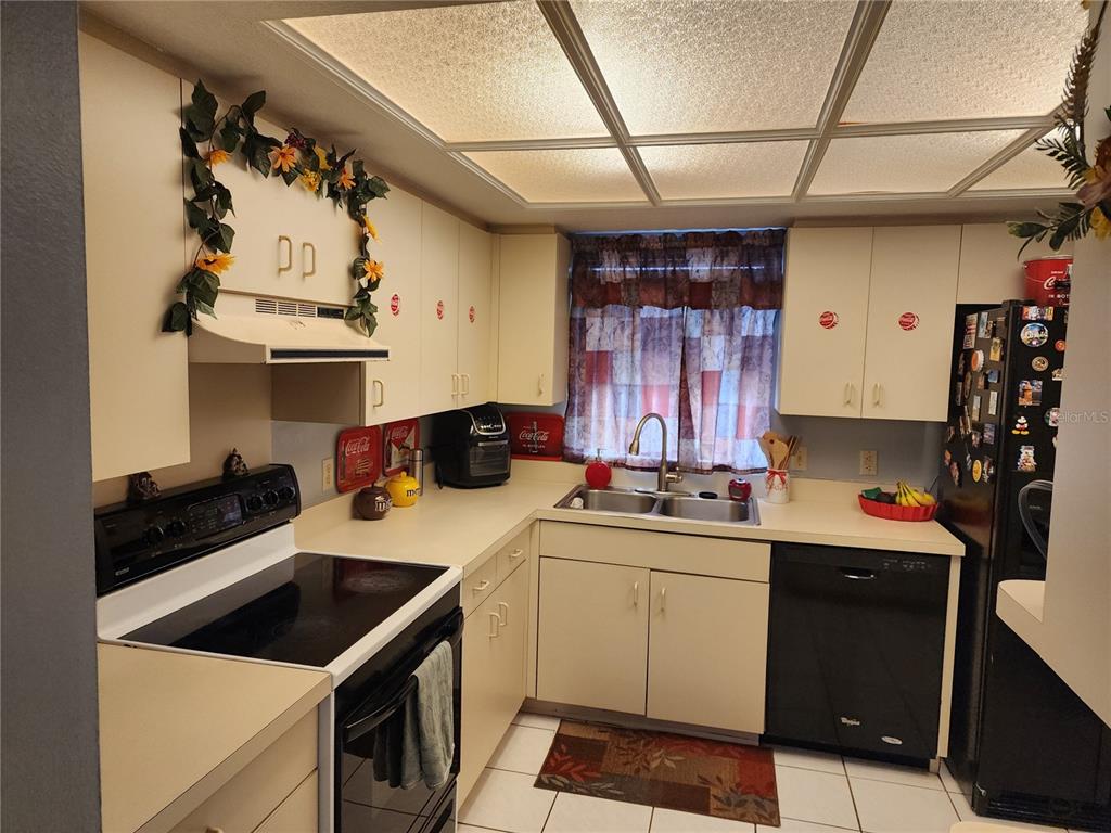 A kitchen features off-white cabinets, black appliances, a double sink, and a tiled ceiling — 2814 WILDER PARK DRIVE, PLANT CITY, FL
