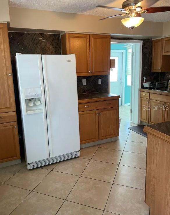 A kitchen features oak cabinets, a white side-by-side refrigerator, and tile flooring — 641 FOLSOM STREET S, ST PETERSBURG, FL