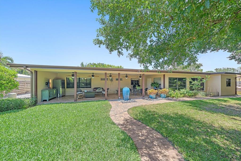 A covered patio with a brick walkway leads to a house with a grassy lawn — 2462 CLEMATIS STREET, SARASOTA, FL