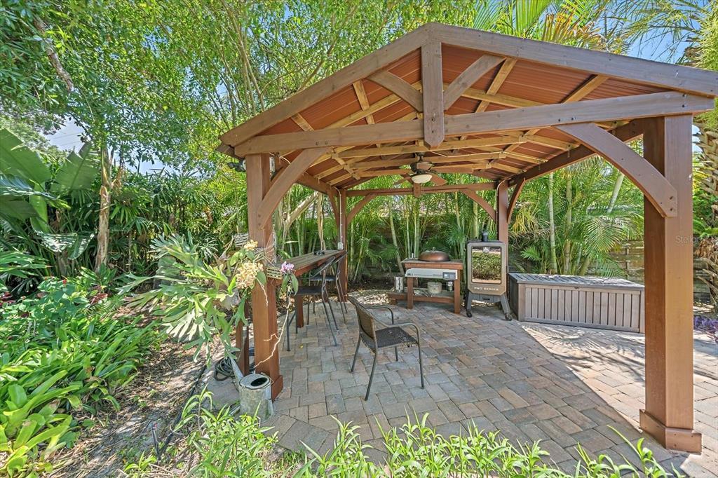 A wooden gazebo with a ceiling fan sits over a paved patio featuring outdoor furniture — 2462 CLEMATIS STREET, SARASOTA, FL