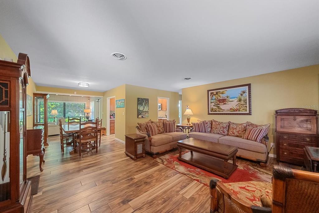A living room and dining area with wood-look flooring, yellow walls, and traditional furniture — 2462 CLEMATIS STREET, SARASOTA, FL