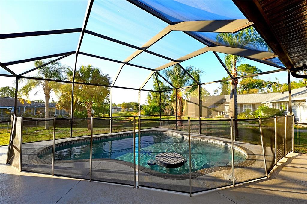 A screened-in swimming pool with a safety fence and a small table in the water — 3522 RENAULT CIRCLE, NORTH PORT, FL