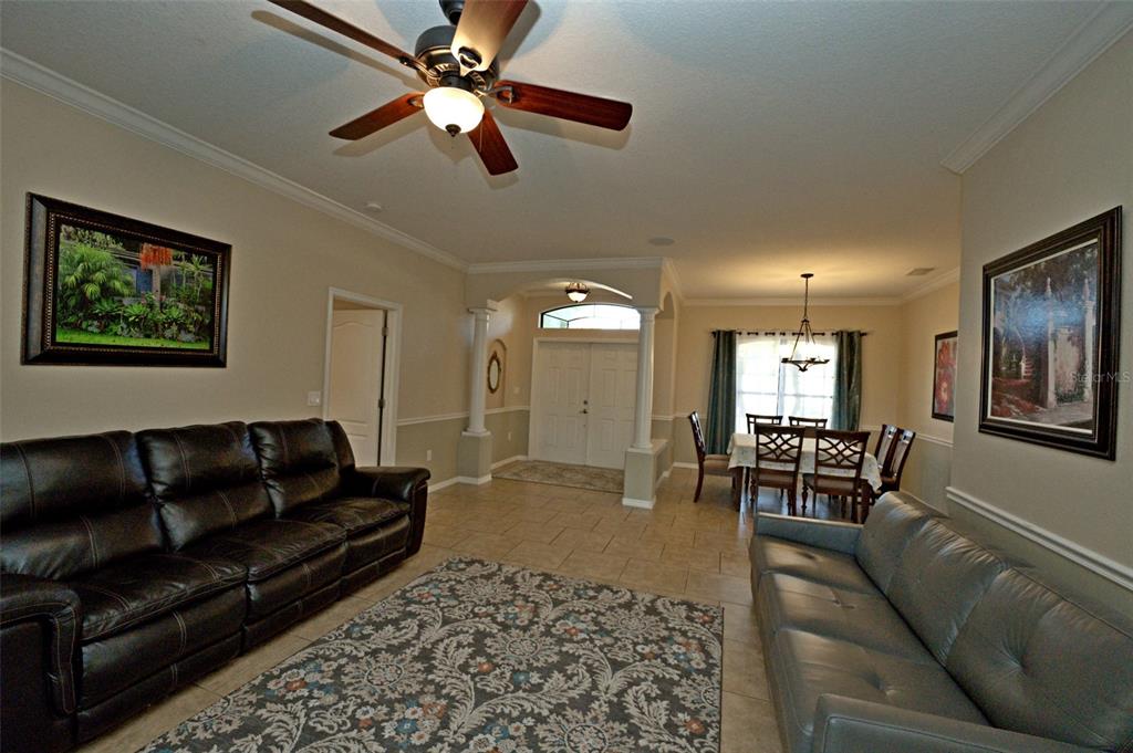 A living room with two leather sofas, a ceiling fan, and an adjacent dining area — 3522 RENAULT CIRCLE, NORTH PORT, FL