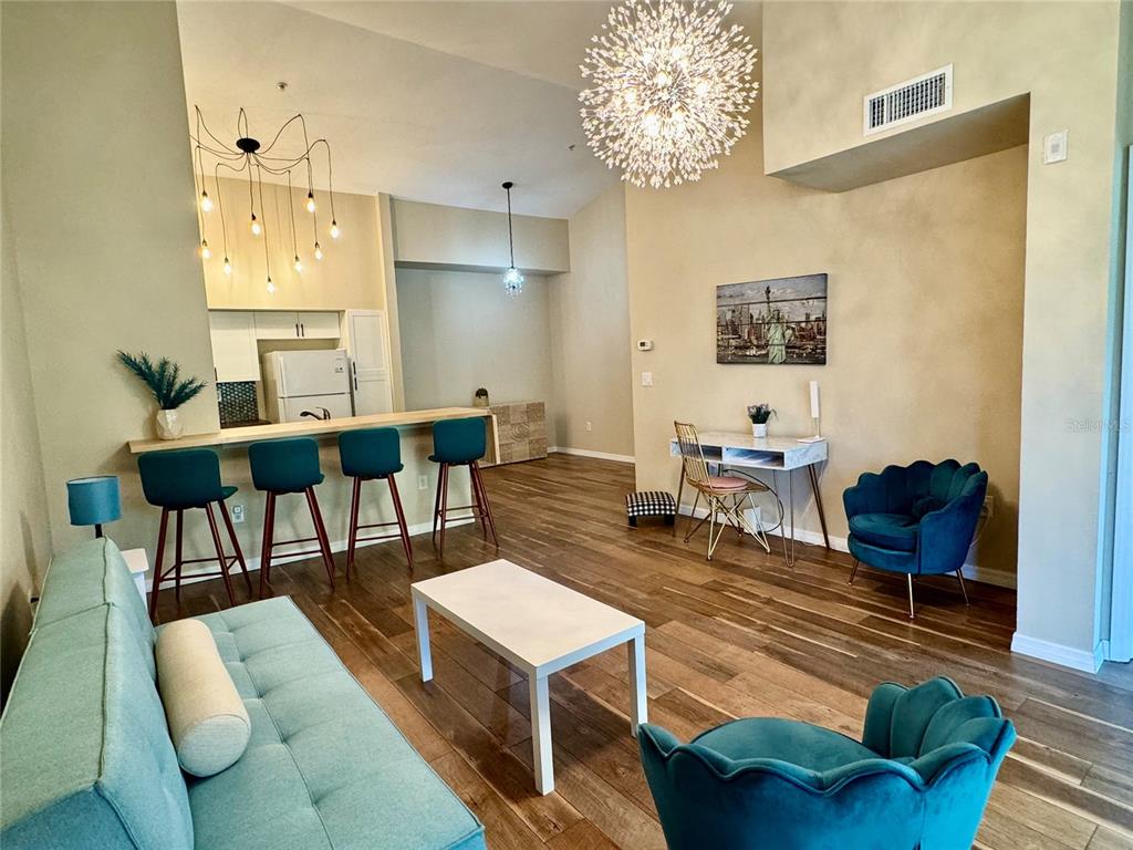 A living room features a beige sofa, wooden coffee table, television, and a sliding glass door — 4106 CENTRAL SARASOTA PARKWAY UNIT # 1028, SARASOTA, FL