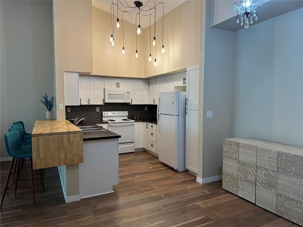 A living area with wood-look flooring, a modern pendant light, and a sliding glass door — 4106 CENTRAL SARASOTA PARKWAY UNIT # 1028, SARASOTA, FL