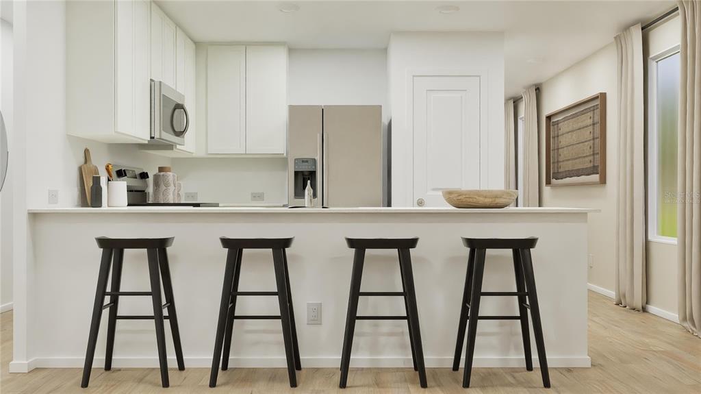 A kitchen features white cabinets, stainless steel appliances, and four black bar stools at a counter — 270 CERAMIC LANE, GROVELAND, FL