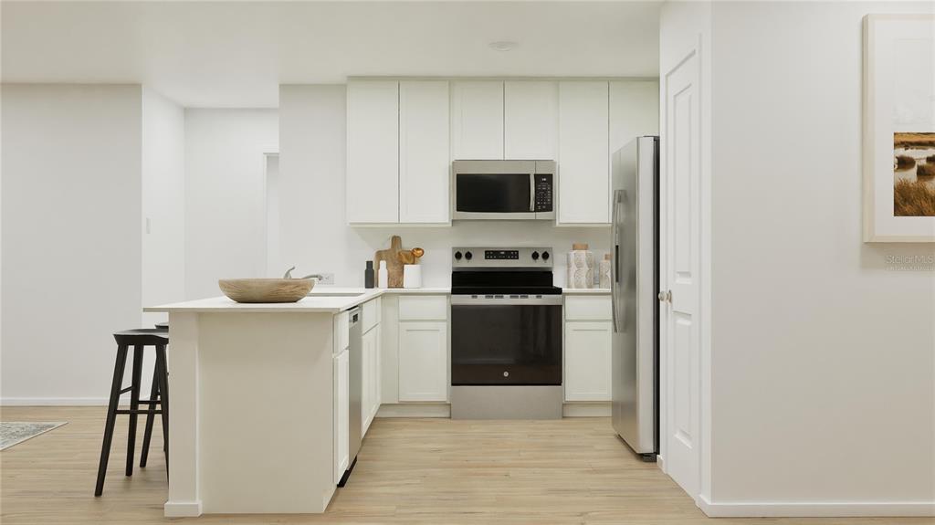 A kitchen features white cabinets, stainless steel appliances, and a peninsula with bar seating — 270 CERAMIC LANE, GROVELAND, FL