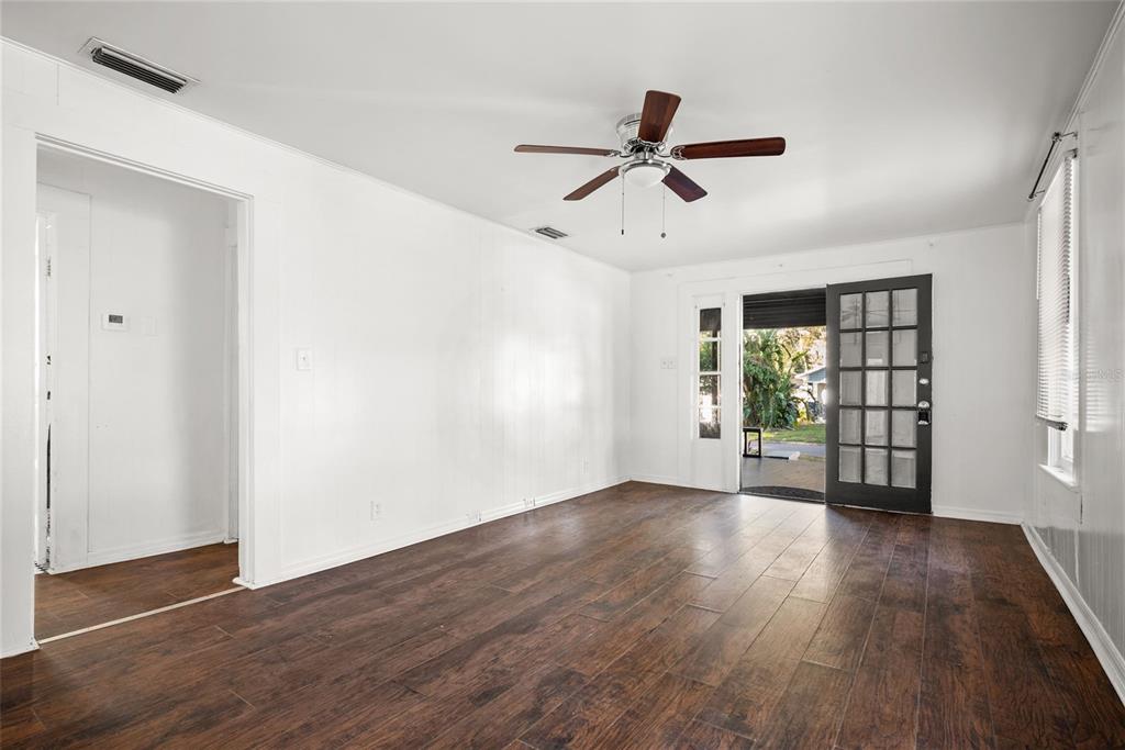 An empty room with white walls, dark wood-look flooring, a ceiling fan, and a glass door — 211 E CLUSTER AVENUE, TAMPA, FL