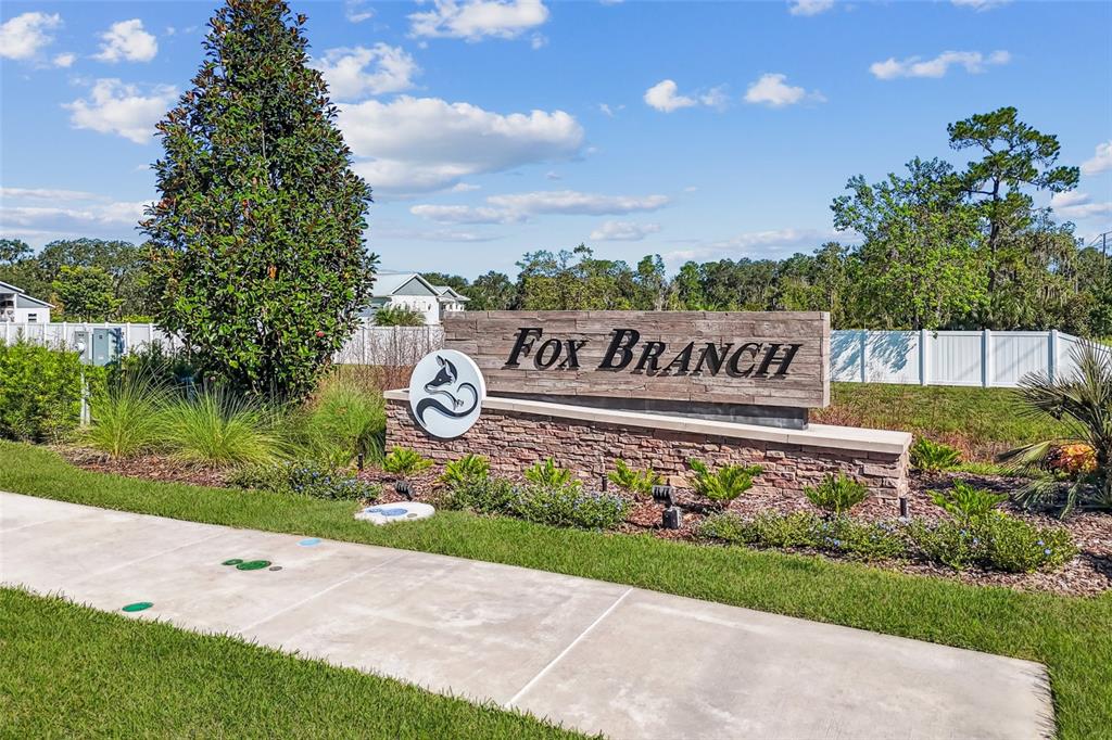 A stone and wood sign for Fox Branch stands beside a sidewalk on a sunny day — 4524 LAKE FOX DRIVE, LAKELAND, FL