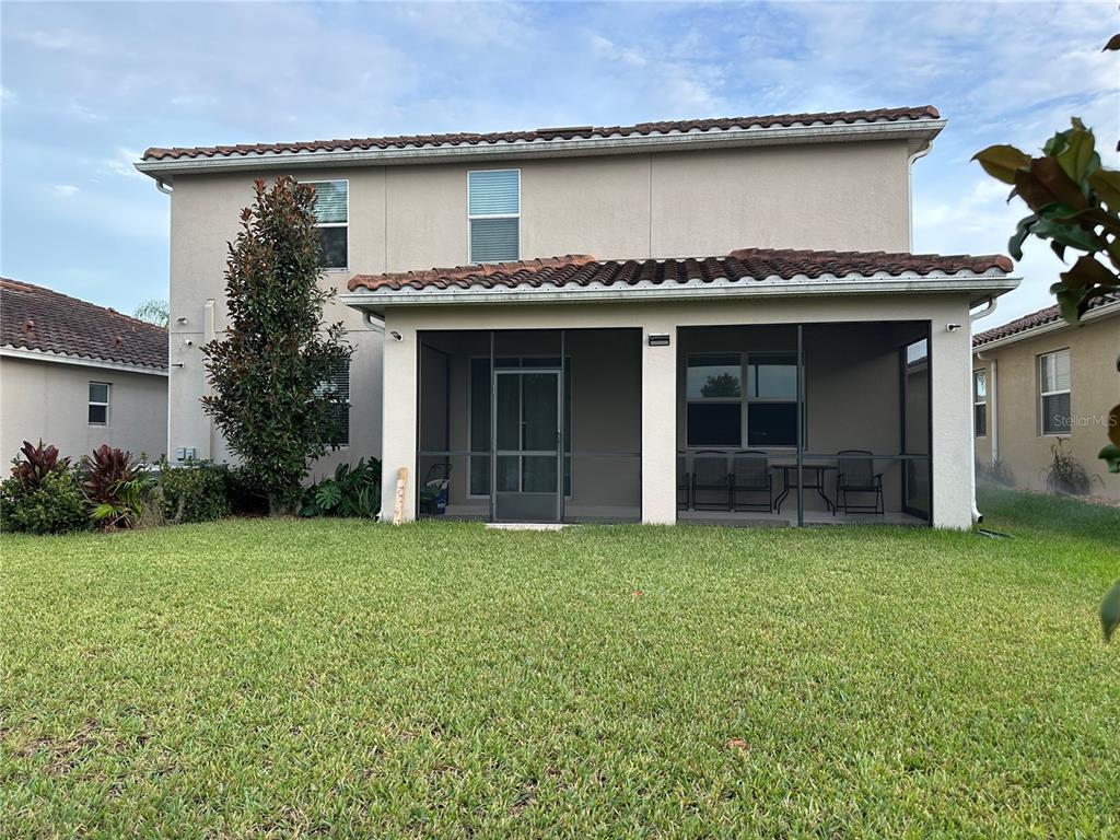 The rear exterior of a two-story house features a screened-in patio and a grassy yard — 2093 LAKE SIDE AVENUE, DAVENPORT, FL