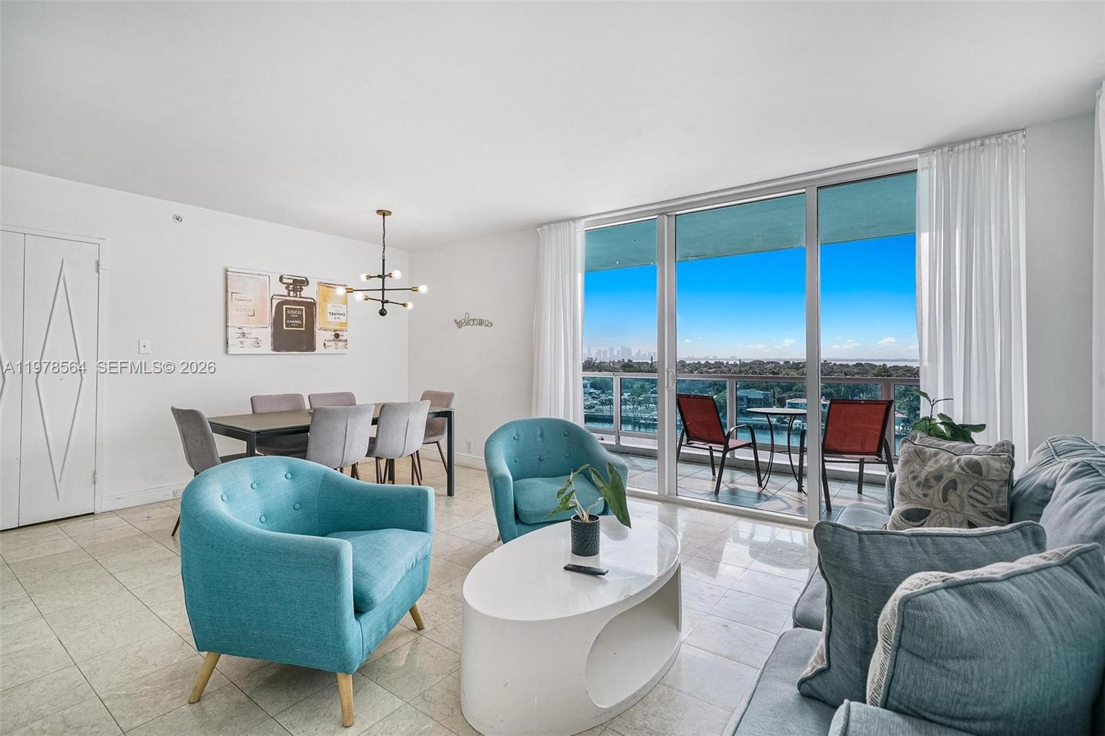 A living and dining area features blue accent chairs, a white coffee table, and balcony views — 5101 Collins Ave # 11B, Miami Beach FL 33140, MIAMI BEACH, FL