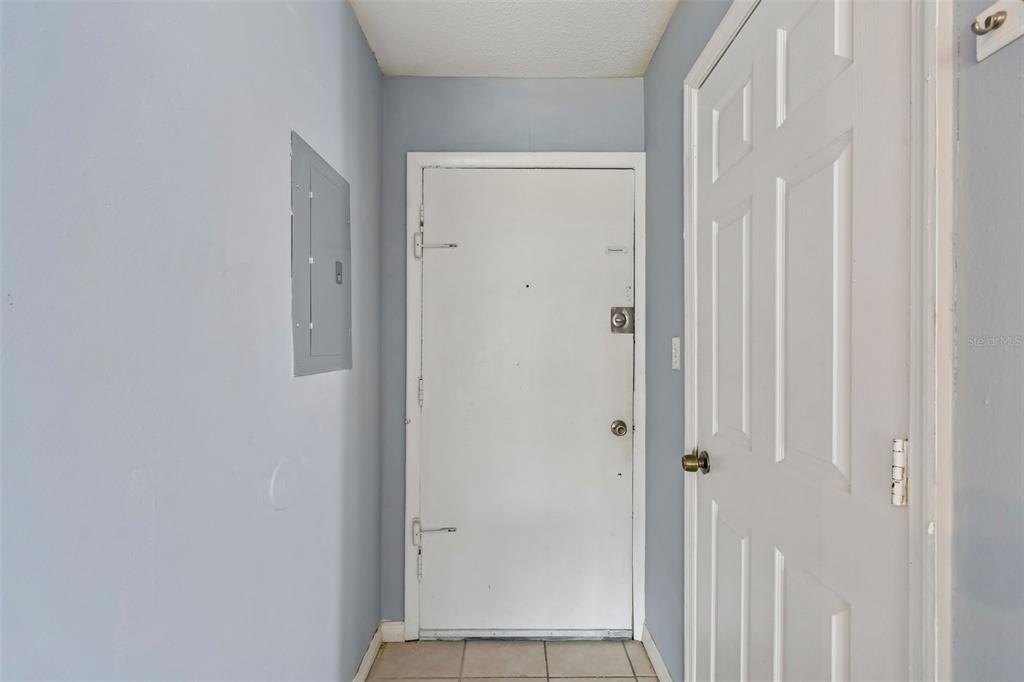 A hallway features light blue walls, a white entry door, and a gray electrical panel — 1695 LEE ROAD UNIT E215, WINTER PARK, FL