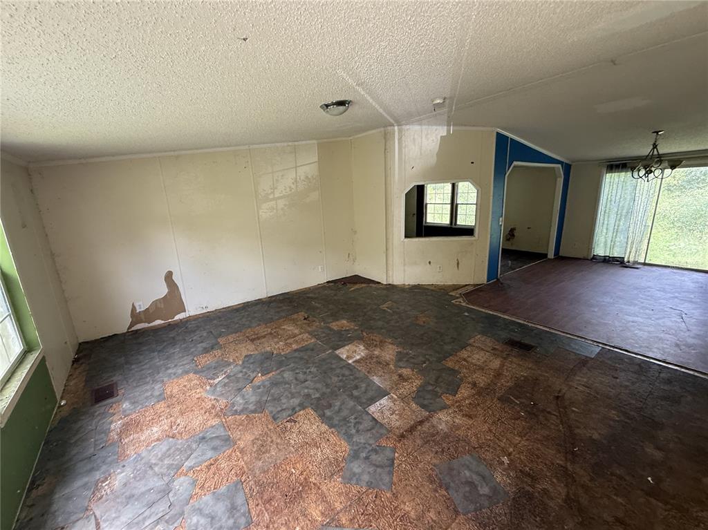 An interior view of a room with damaged wall panels and exposed subflooring — 11410 ROCKRIDGE ROAD, LAKELAND, FL