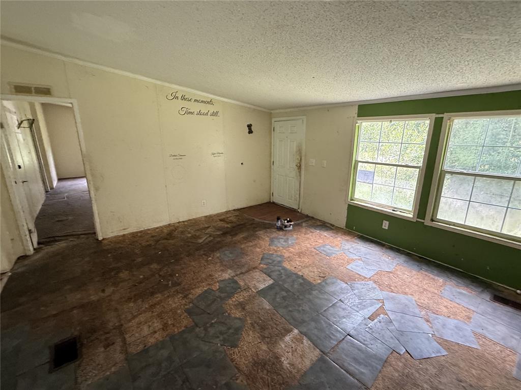 An interior view of a room with unfinished flooring, white walls, and two large windows — 11410 ROCKRIDGE ROAD, LAKELAND, FL