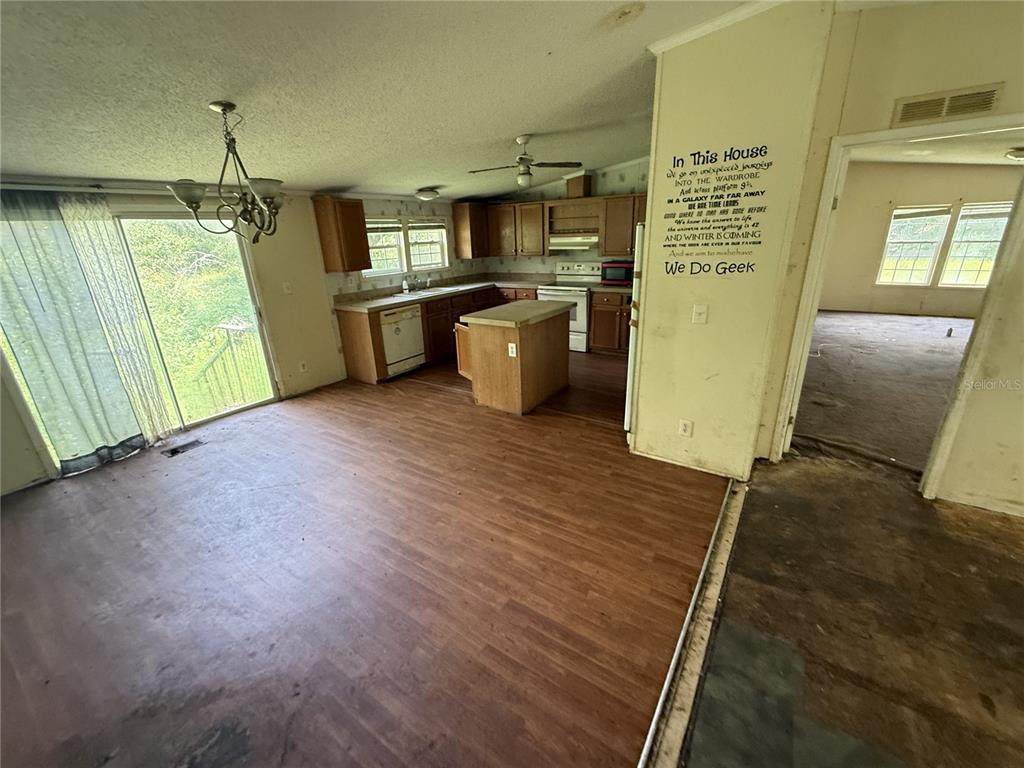 A kitchen and dining area with wood-look flooring, a center island, and a sliding glass door — 11410 ROCKRIDGE ROAD, LAKELAND, FL