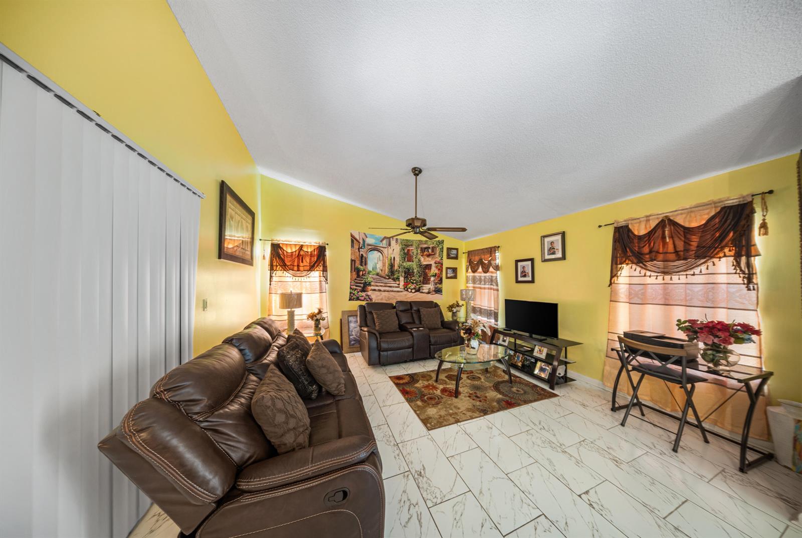 A living room features yellow walls, white marble-look tile flooring, and brown leather furniture — 4255 Willow Pond Circle # A, West Palm Beach FL 33417, WEST PALM BEACH, FL