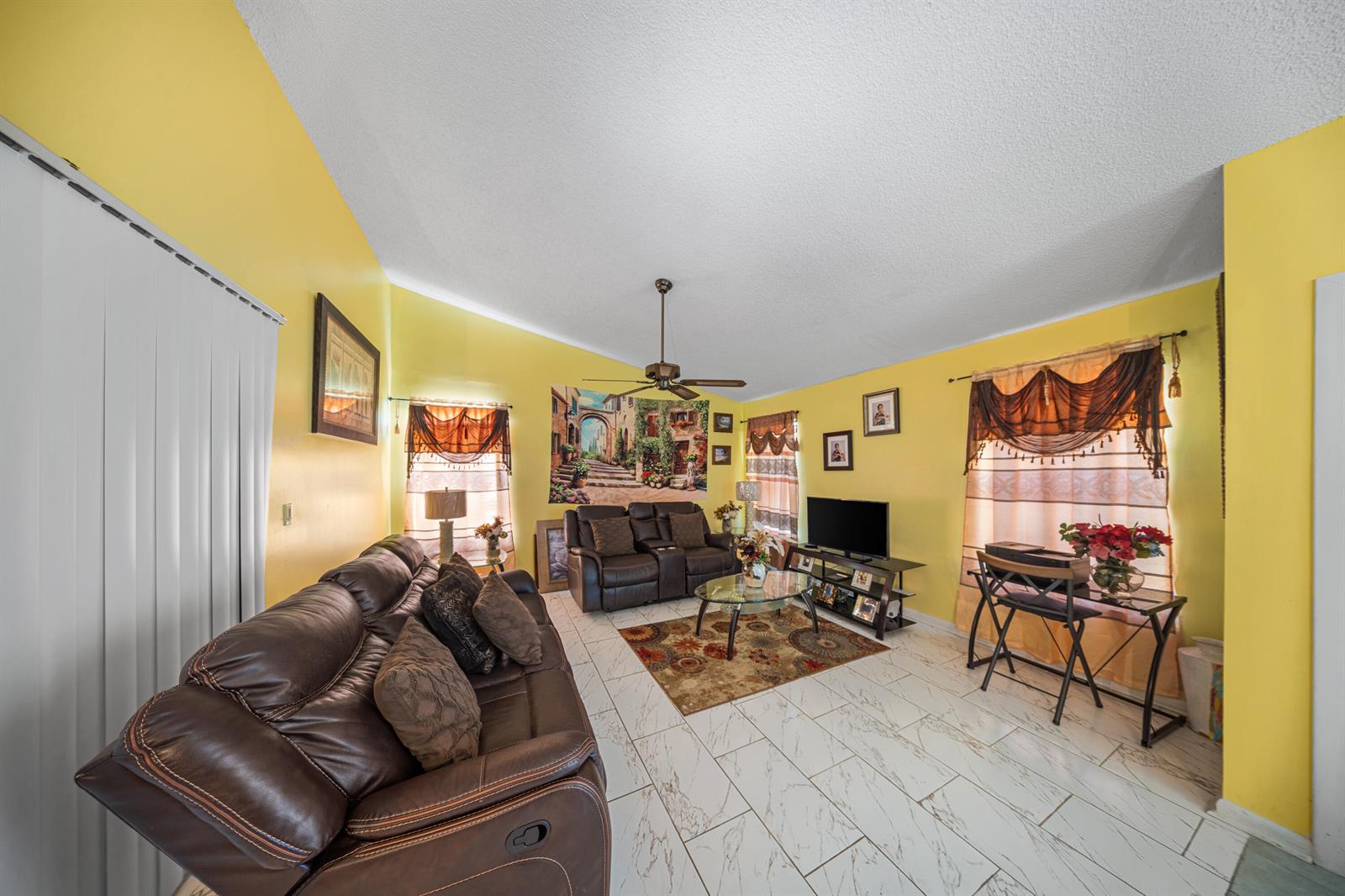 A living room features yellow walls, white tile flooring, brown leather furniture, and a ceiling fan — 4255 Willow Pond Circle # A, West Palm Beach FL 33417, WEST PALM BEACH, FL