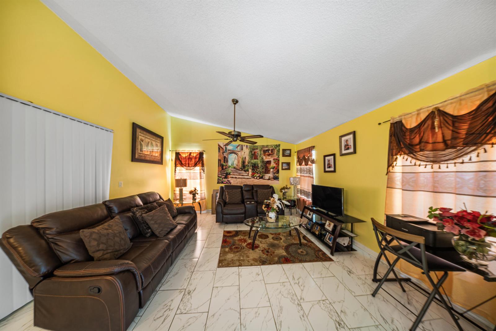A living room with yellow walls, white marble-style tile floors, and brown leather furniture — 4255 Willow Pond Circle # A, West Palm Beach FL 33417, WEST PALM BEACH, FL