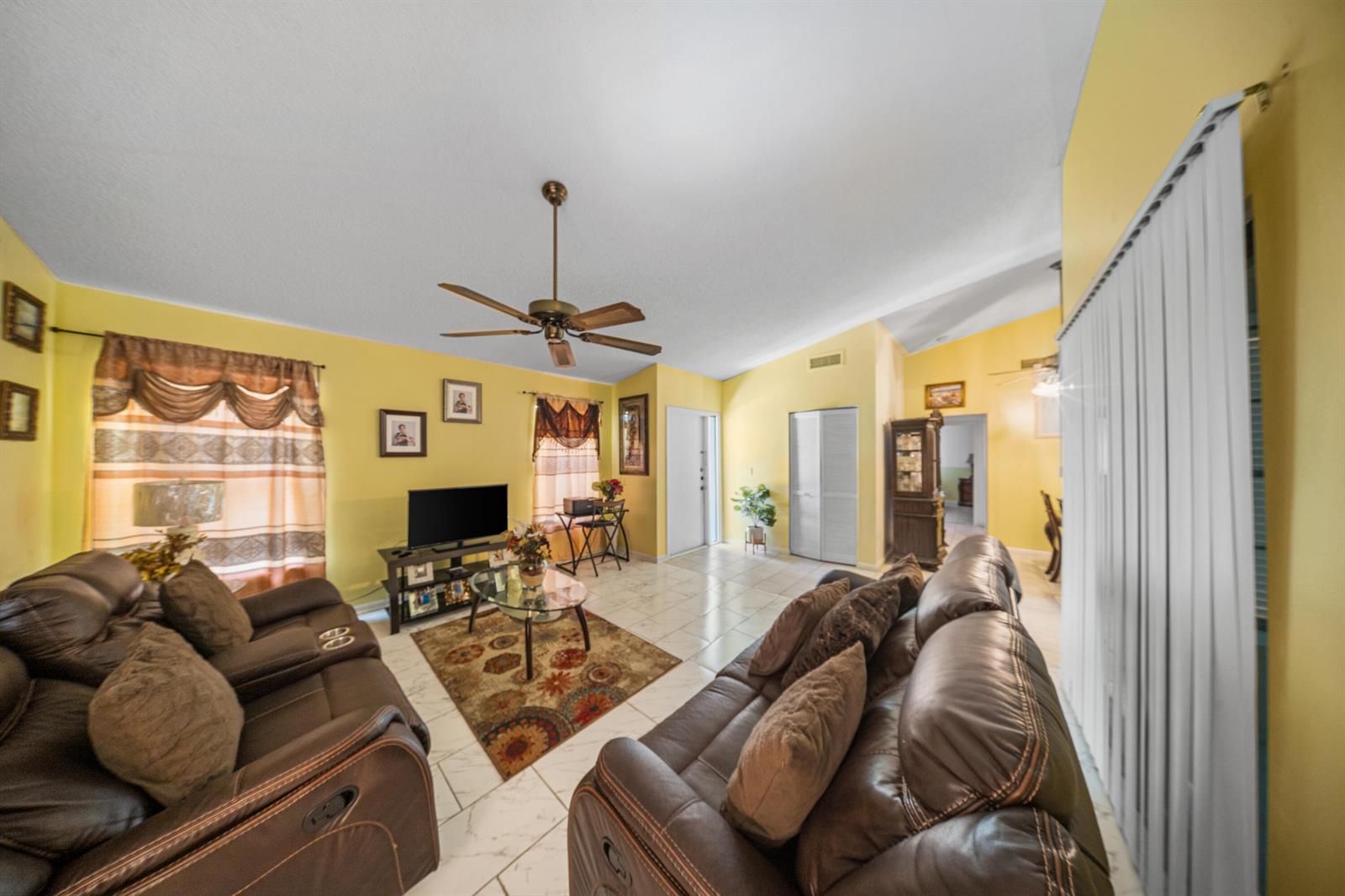 A living room features yellow walls, tile flooring, two brown leather sofas, and a ceiling fan — 4255 Willow Pond Circle # A, West Palm Beach FL 33417, WEST PALM BEACH, FL