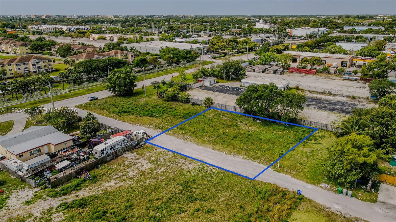 An aerial view shows a vacant rectangular lot outlined in blue next to a residential property — NW 19th Ave, Pompano Beach FL 33069, POMPANO BEACH, FL
