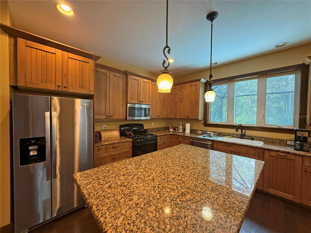 A kitchen features wood cabinets, granite countertops, stainless steel appliances, and a large center island — 11691 SW 52ND AVENUE, OCALA, FL