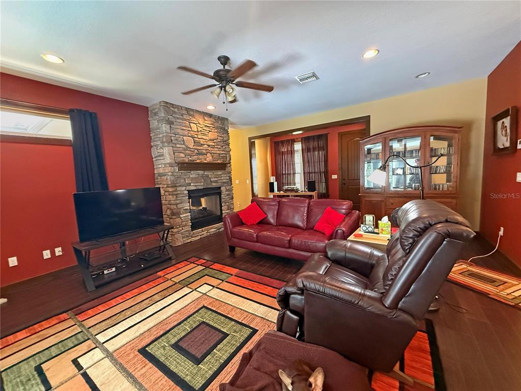 A living room features a stone fireplace, red walls, dark wood floors, and leather furniture — 11691 SW 52ND AVENUE, OCALA, FL