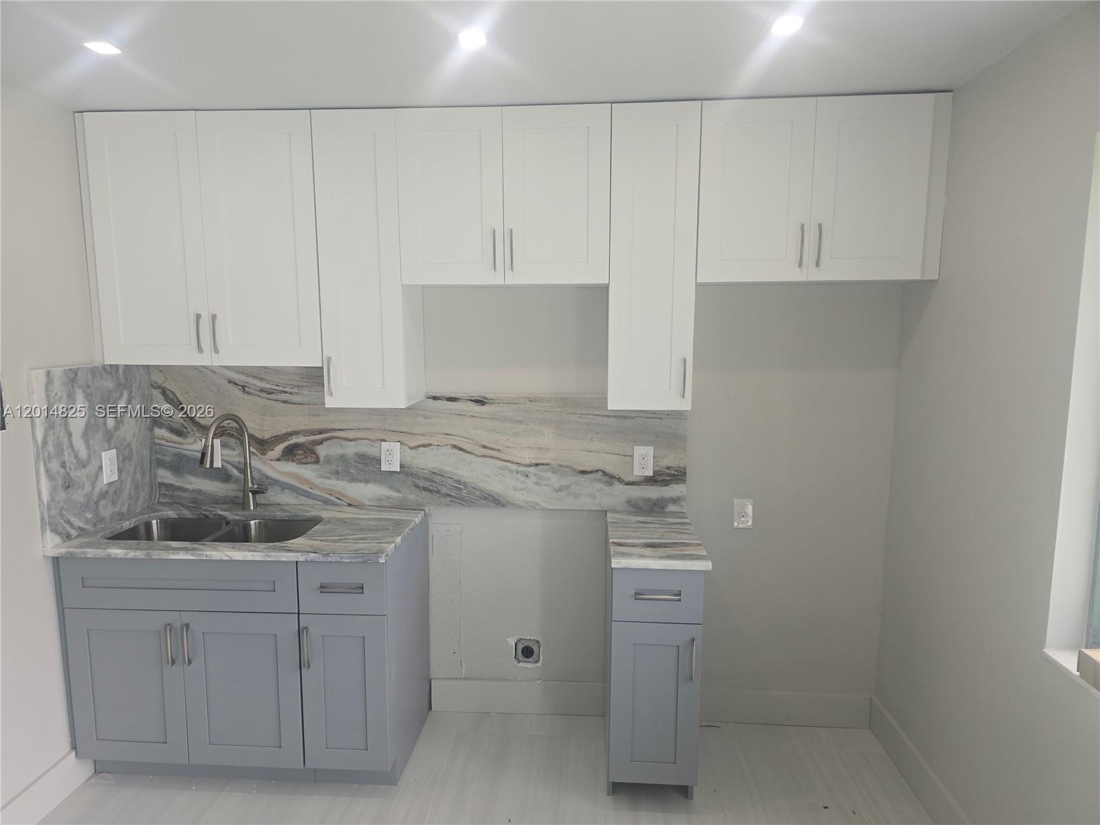 A kitchen features gray lower cabinets, white upper cabinets, and a marble-patterned backsplash — 3300 SE 6th St, Pompano Beach FL 33062, POMPANO BEACH, FL