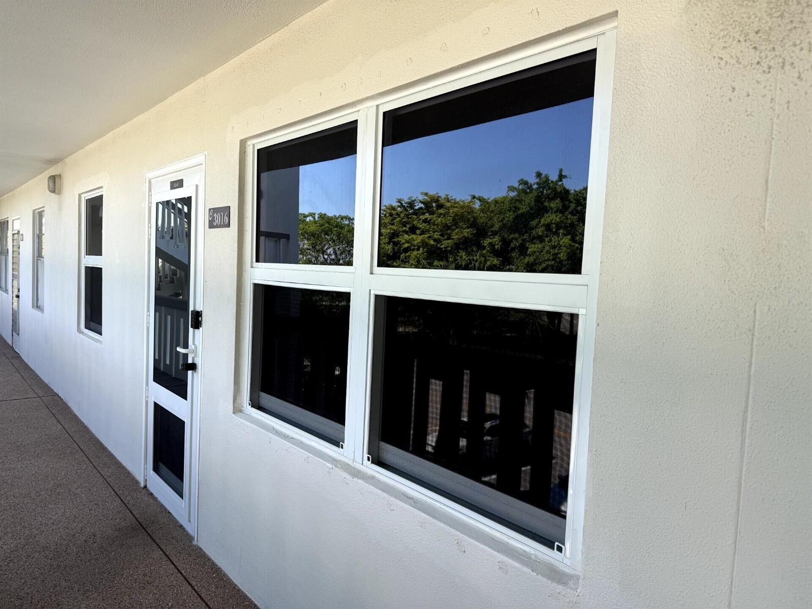 An exterior view of a white apartment building with a door and a large window — 3016 Ashby C # 3016, Deerfield Beach FL 33442, DEERFIELD BEACH, FL