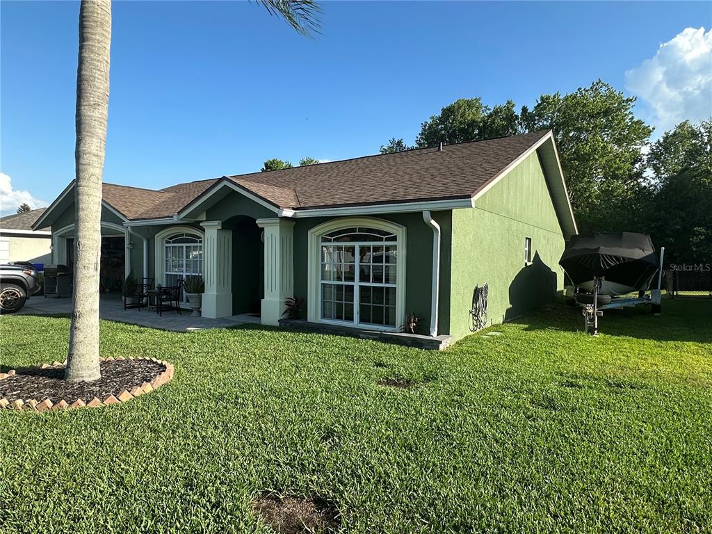 A green single-story house with a brown roof, white columns, and a boat on a trailer — 3084 THOROUGHBRED LOOP W, LAKELAND, FL